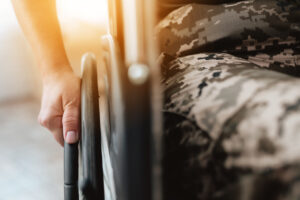 Woman Veteran In Wheelchair Returned From Army. Close Up Photo Veteran Woman In A Wheelchair.